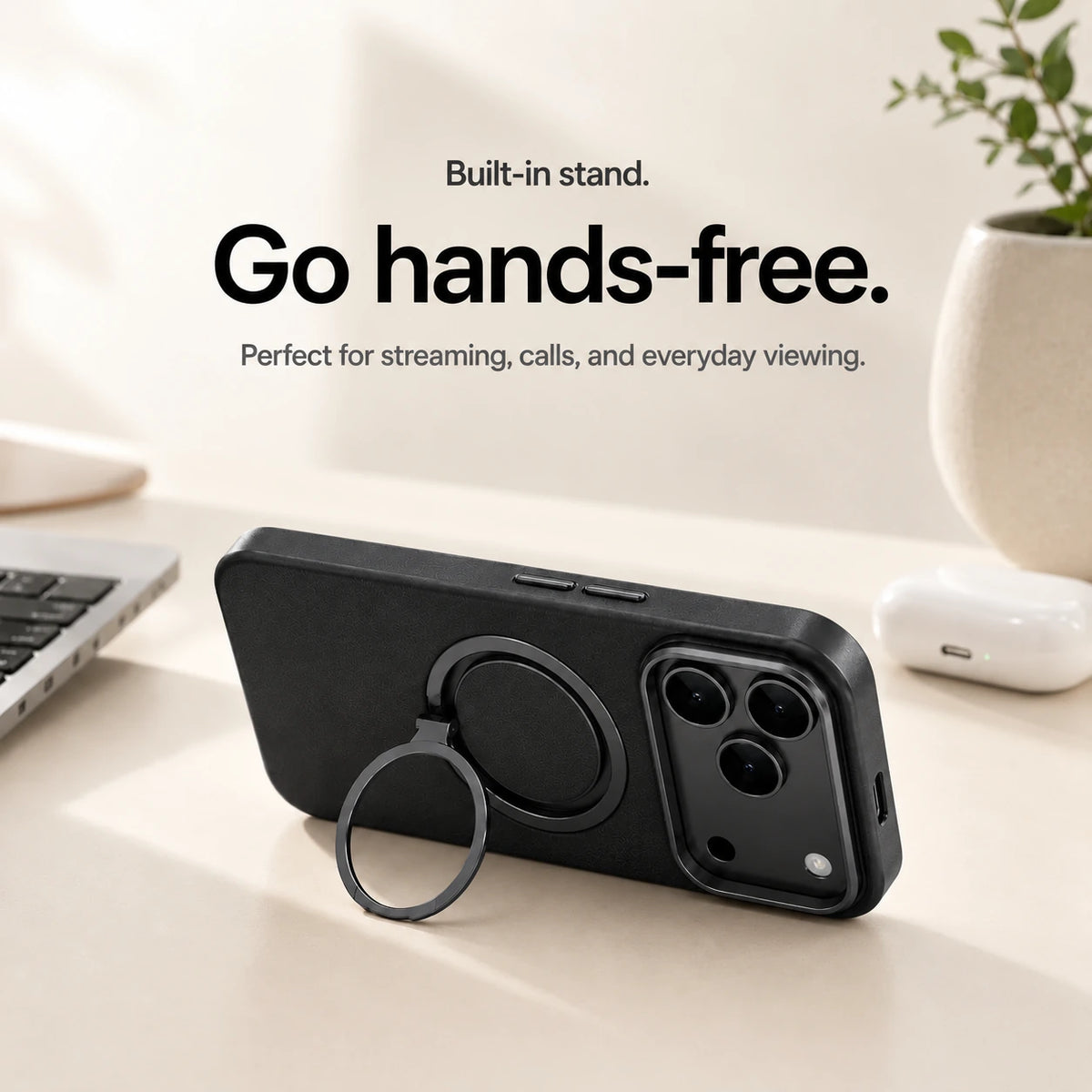 Black leather phone case propped horizontally on its ring stand beside a laptop #color_Midnight Black