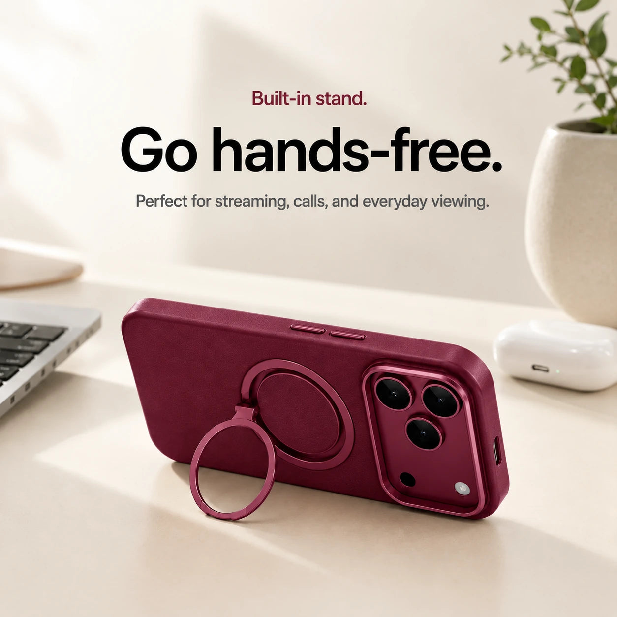 Burgundy leather phone case propped horizontally on its ring stand beside a laptop #color_Cherry Red