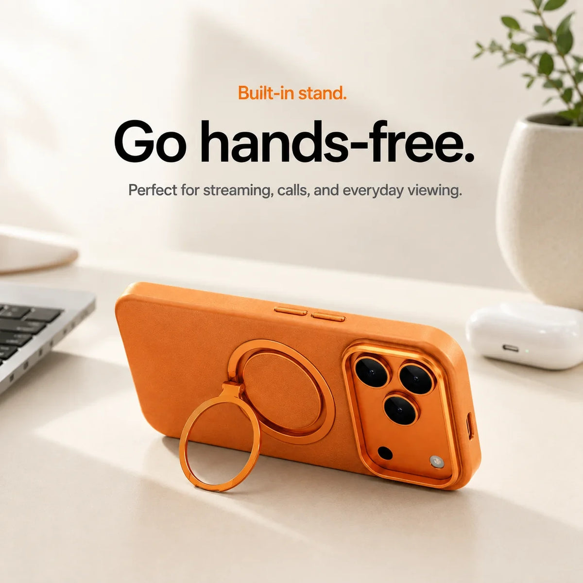 Orange leather phone case propped horizontally on its ring stand beside a laptop #color_Cosmic Orange